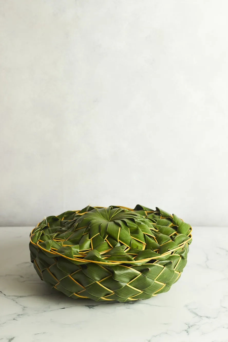 Green woven basket on a marble surface with a white background