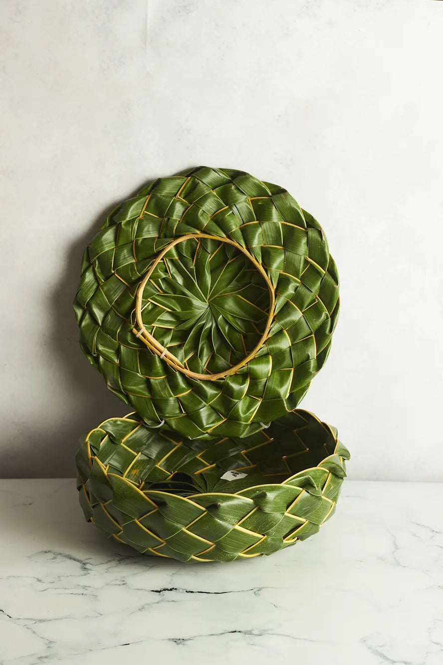 Two green woven baskets on a marble surface with a white background
