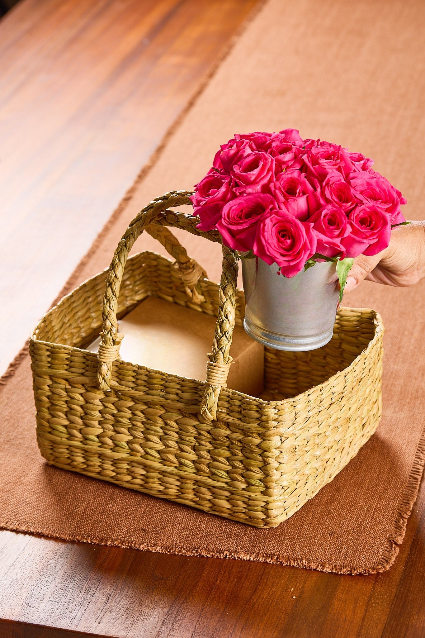 Woven basket with a roses tin on a wooden surface