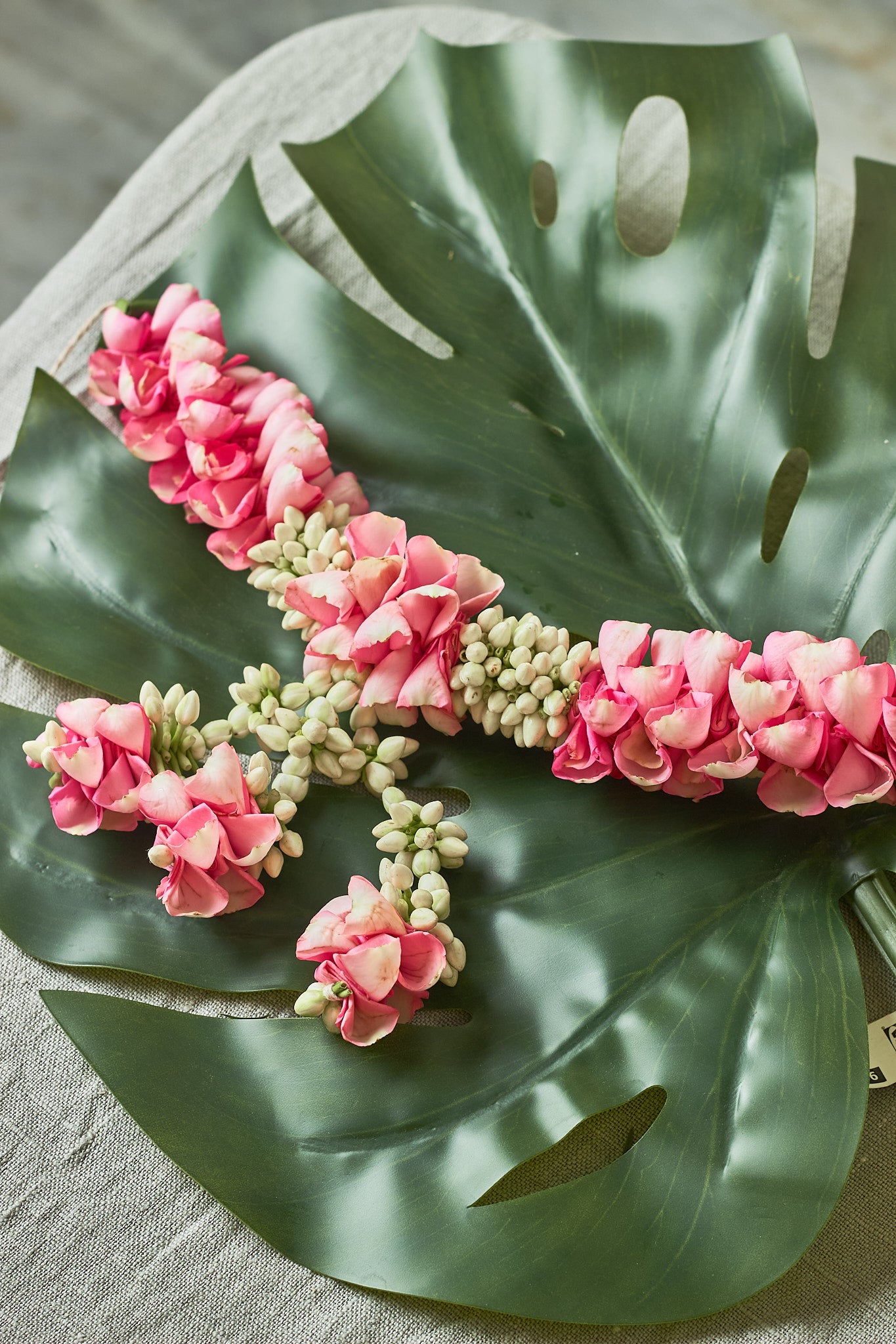 Pink-White-Gajra - Mahua Floral Studio-A decorative hair accessory featuring a green leaf and pink flower sticks.