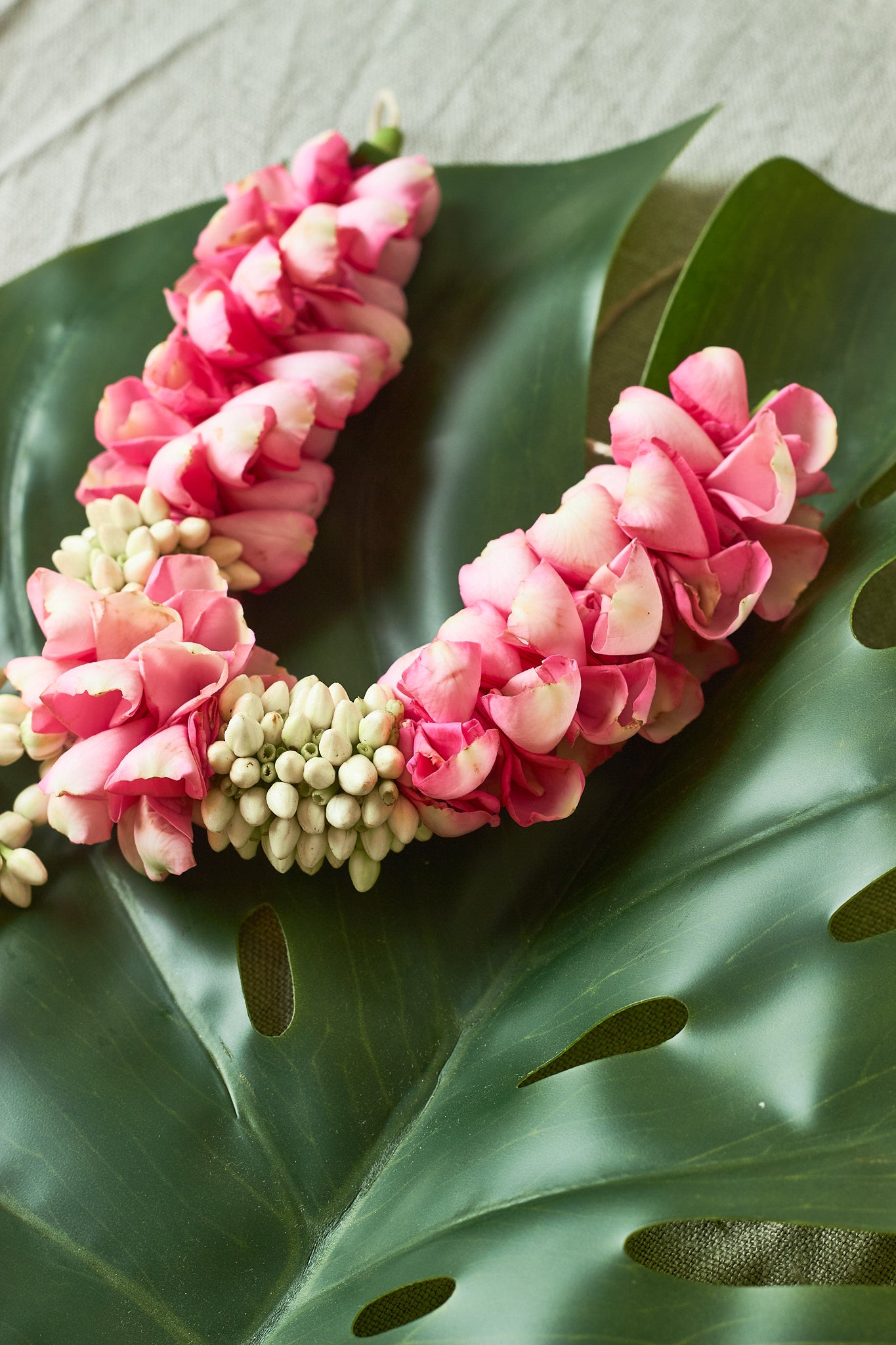 Pink-White-Gajra-Mahua Floral Studio-A decorative hair accessory featuring a green leaf and pink flower sticks.