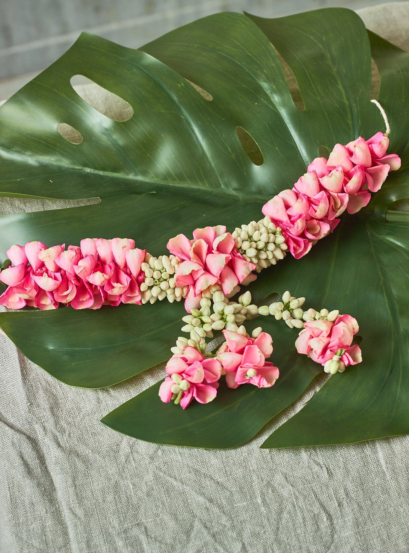 Pink-White-Gajra-Mahua Floral Studio-A decorative hair accessory featuring a green leaf and pink flower sticks.