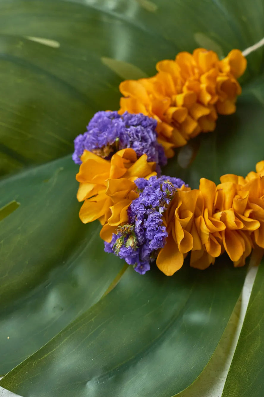 Orange and purple flower lei on a green leaf background