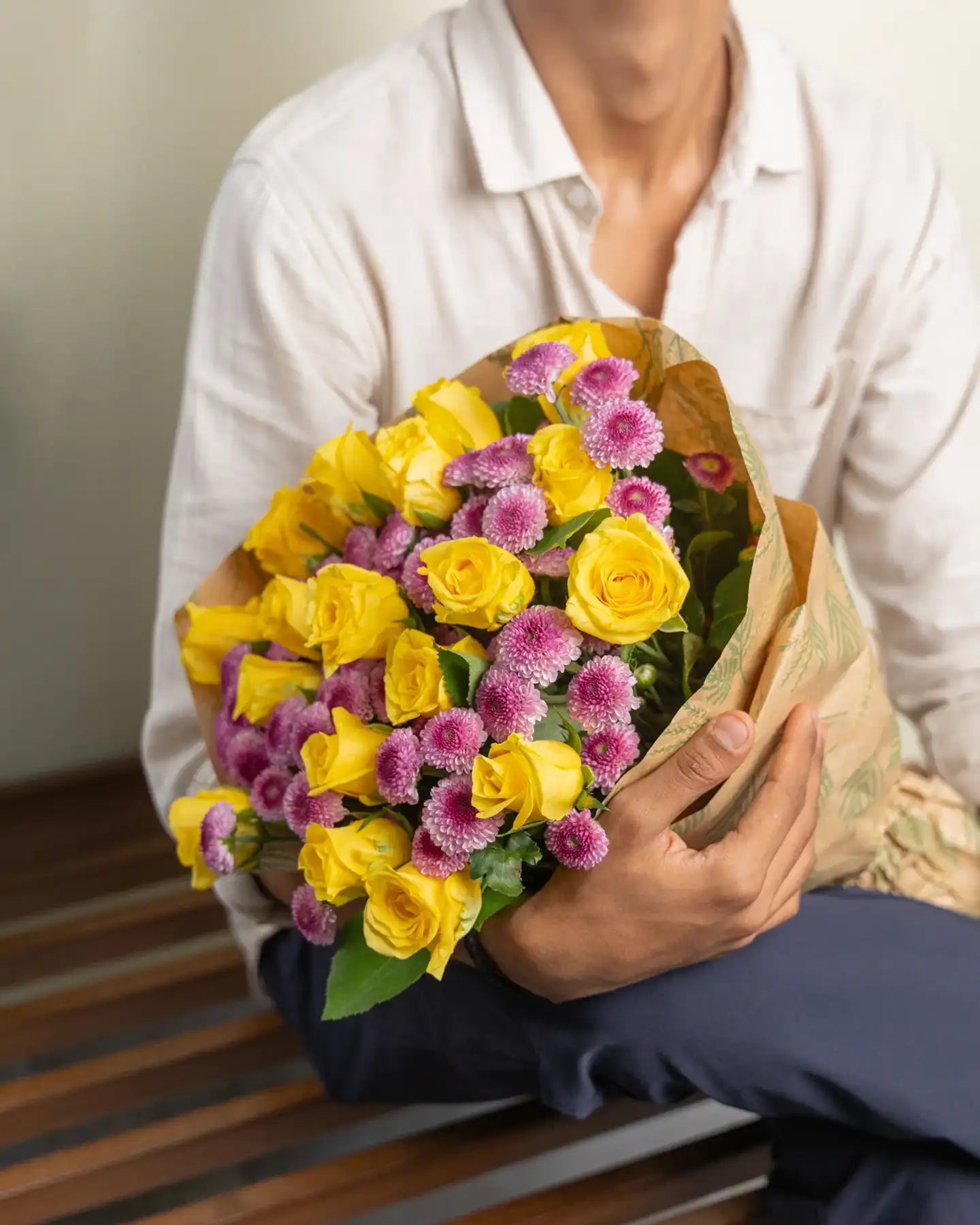 Person holding a bouquet of yellow and pink flowers
