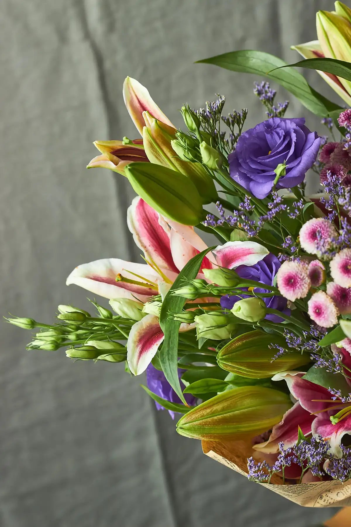 Bouquet of flowers with pink, purple, and green colors against a gray background