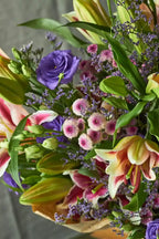 Bouquet of colorful flowers including roses and lilies with a blurred background