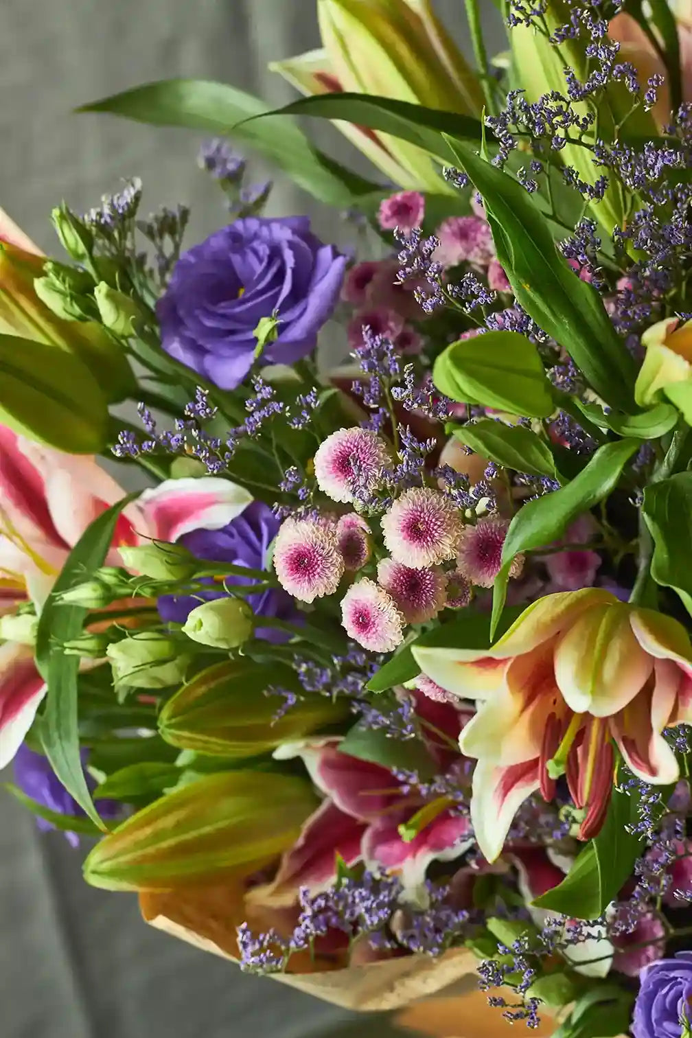 Bouquet of colorful flowers including roses and lilies with a blurred background