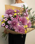 Bouquet of flowers held by a person against a neutral background